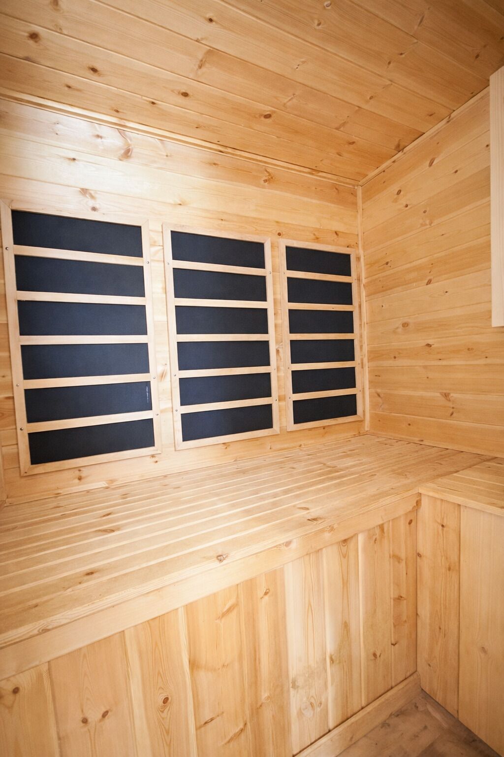 A wooden sauna room with a bench and two large windows.