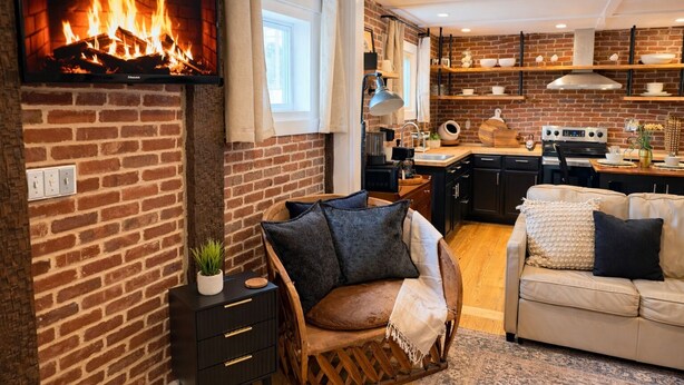 Un salon chaleureux avec une cheminée, un canapé, une table à manger et une cuisine aux murs en briques.