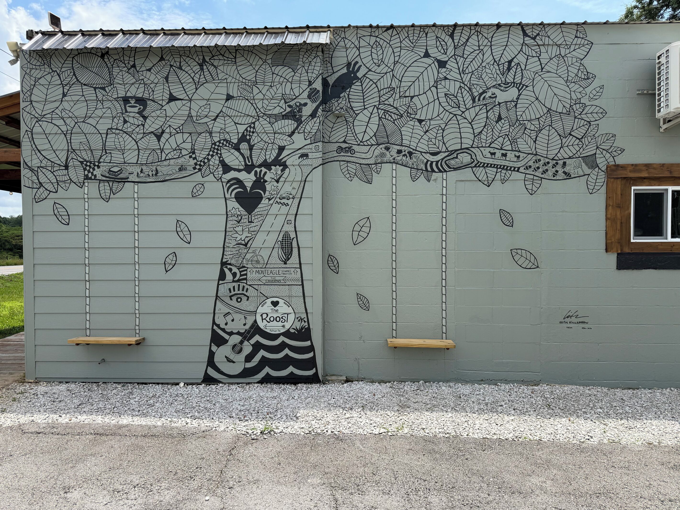 A building with a mural of a tree and various objects.