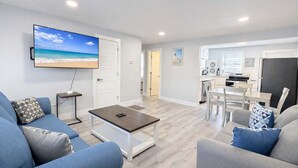 Ett modernt vardagsrum med en platt-TV, ett soffbord och en soffa.