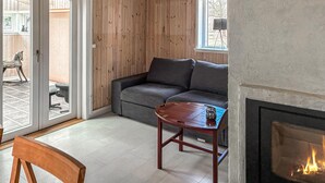 A living room with a gray sofa, a wooden coffee table, and a fireplace. - 2 bedroom awesome home in Stenlille (Stenlille)