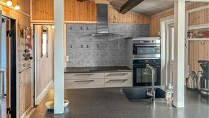 A modern kitchen with wooden accents, grey tiles, stainless steel appliances, and a black countertop. - 2 bedroom awesome home in Stenlille (Stenlille)