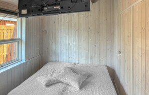 A bedroom with a bed, a window, and a wooden wall.