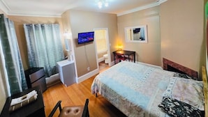A hotel room with a bed, a desk, a television, a bathroom, and a window.