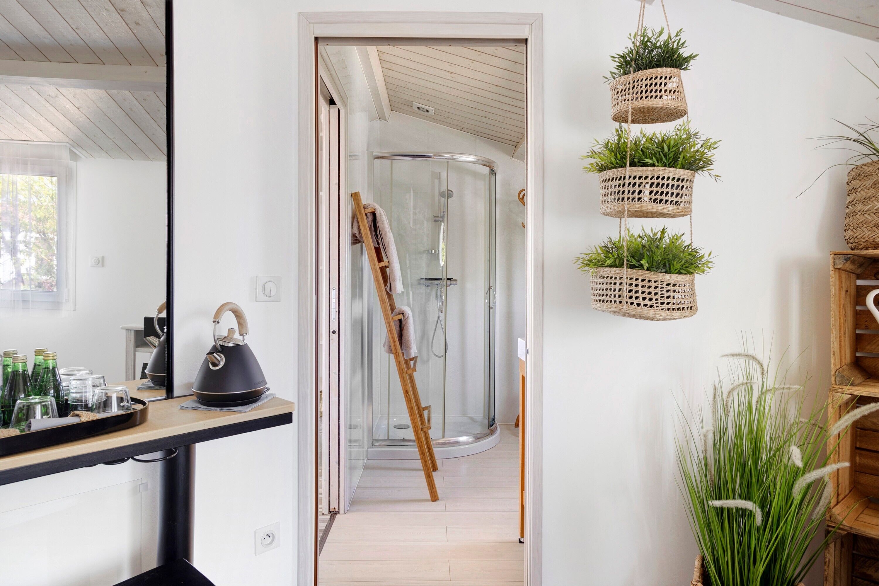 Une salle de bain moderne avec une douche en verre, une échelle en bois et une bouilloire sur le comptoir.