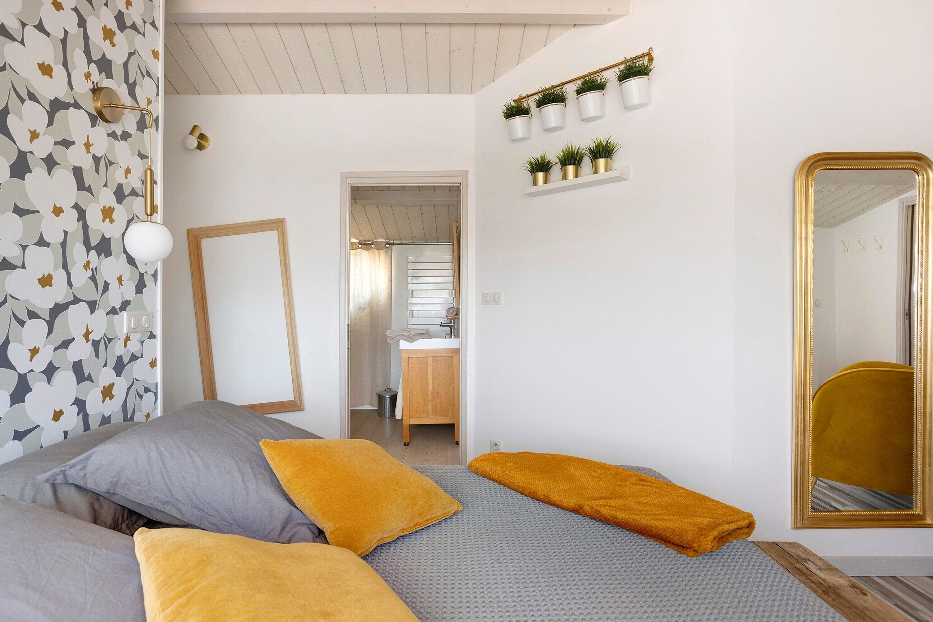 Un dormitorio con dos camas, un espejo y un baño visible a través de una puerta abierta.
