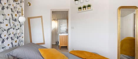 Ein Schlafzimmer mit zwei Betten, einem Spiegel und einem durchgegangenen Tür zu sehendem Badezimmer.