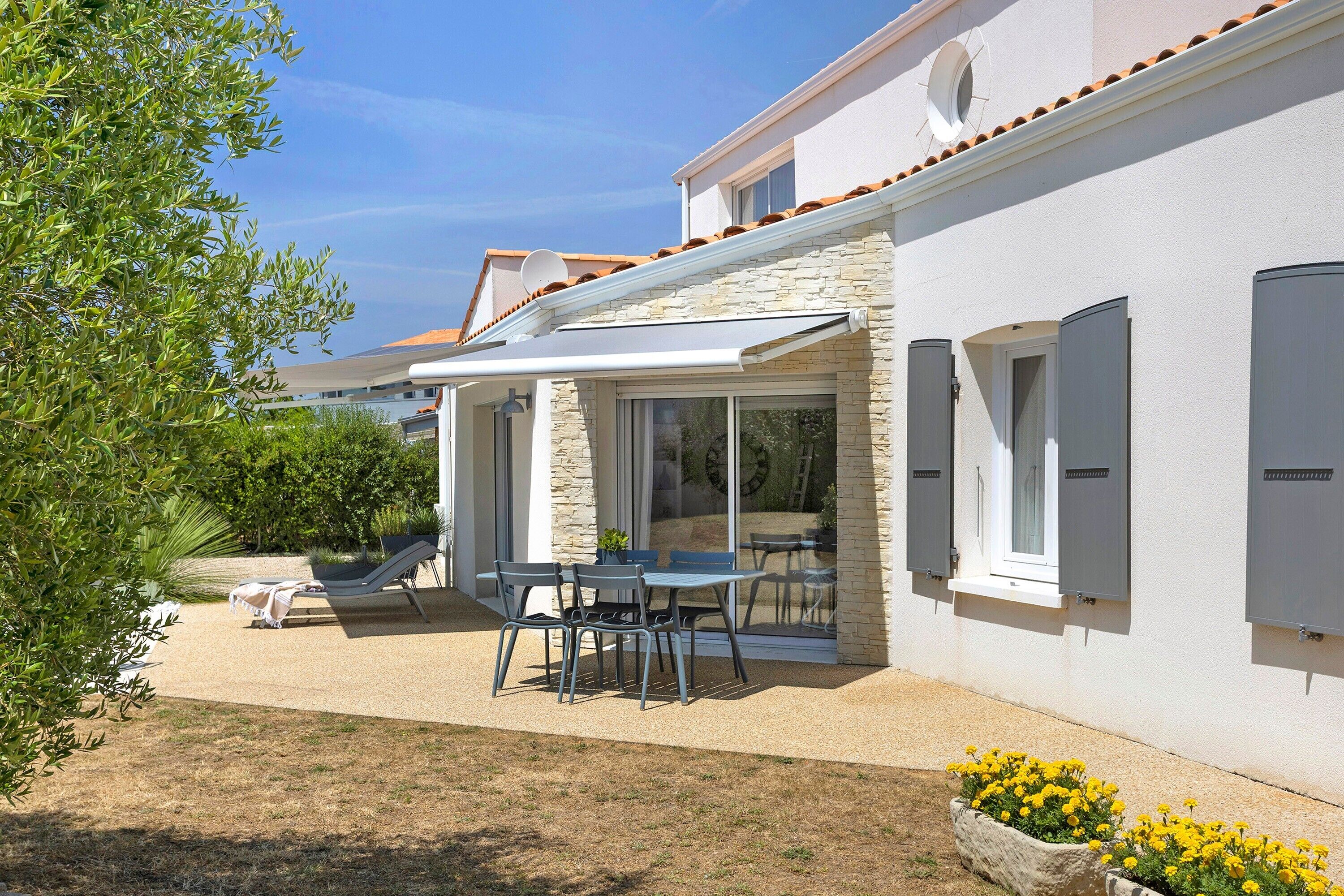 Une maison dotée d’un patio couvert, de mobilier d’extérieur et d’un jardin.