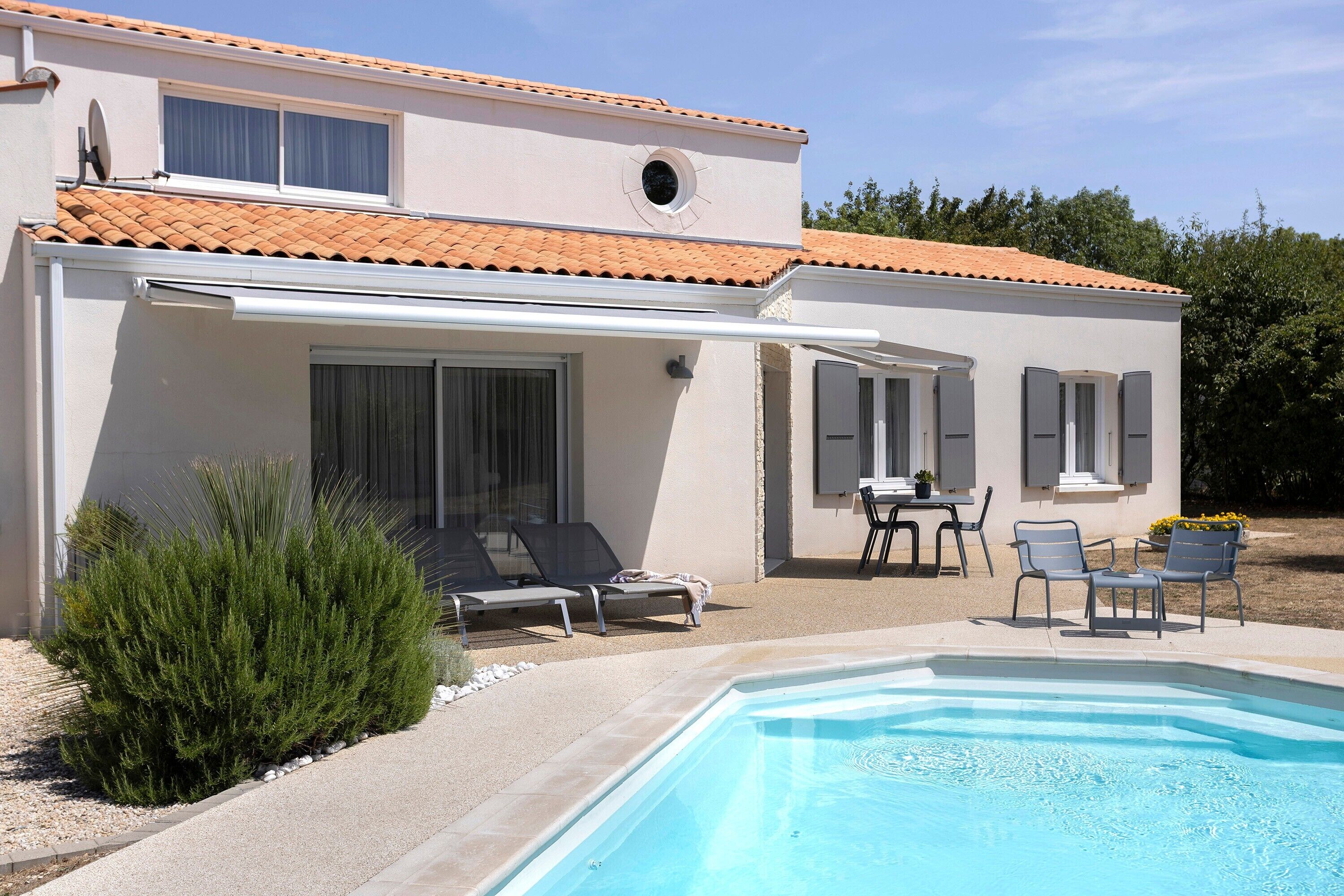 Ein zweistöckiges Gebäude mit Pool, Außenbereich zum Sitzen und einer überdachten Terrasse.