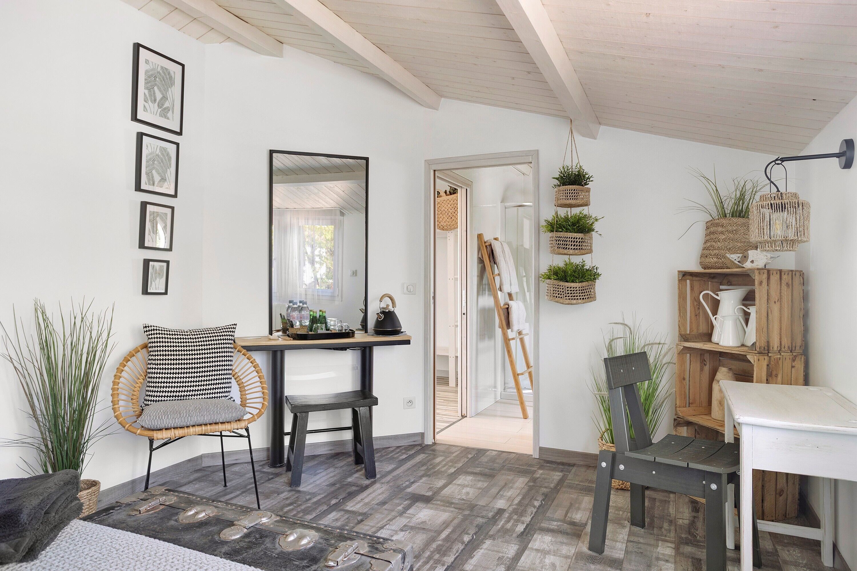 A room with a wooden floor, a dining table, two chairs, a mirror, and a door leading to another room.