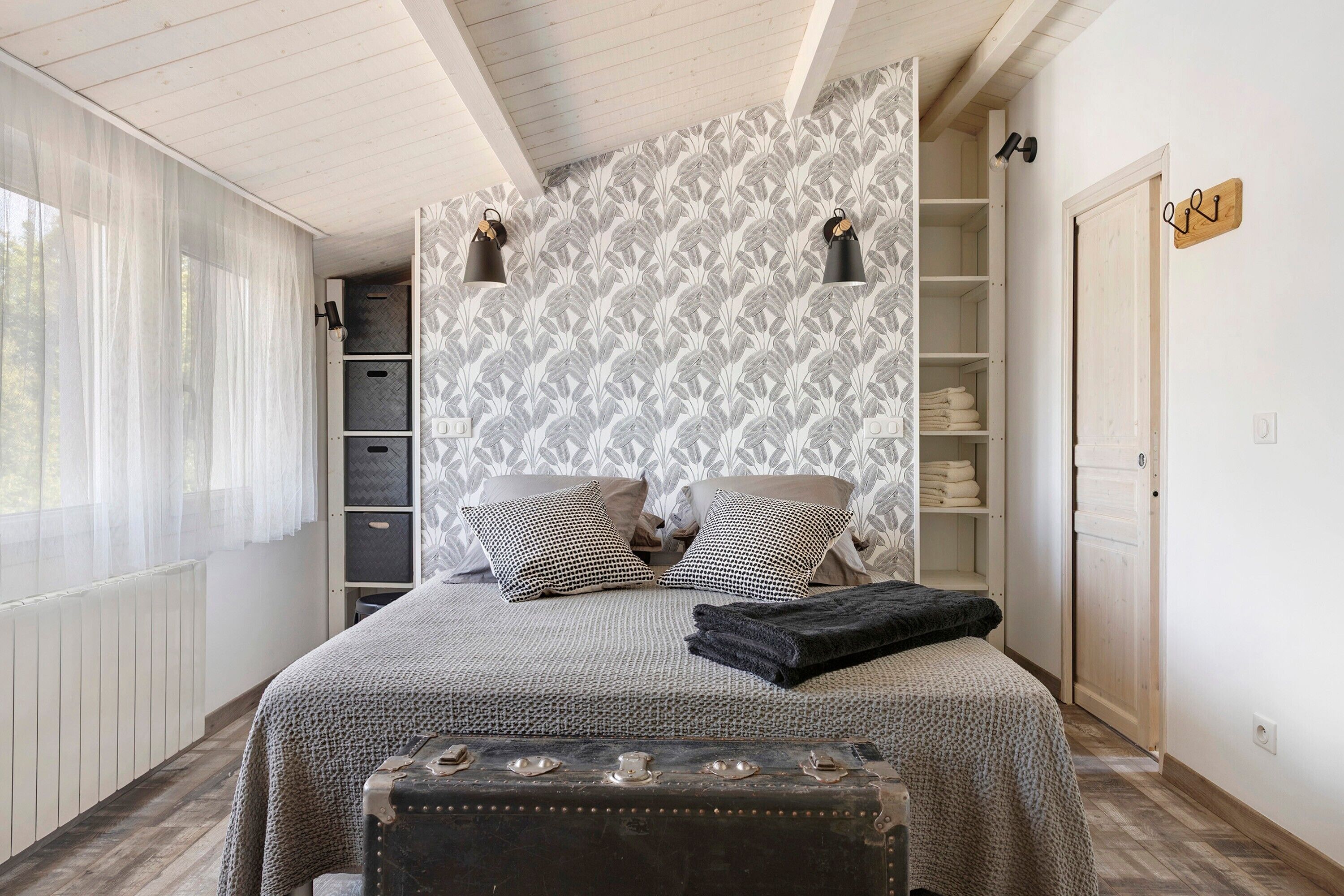 Ein Schlafzimmer mit einem Bett, Kissen, einer Bank, einem Kleiderschrank und einer Heizung.