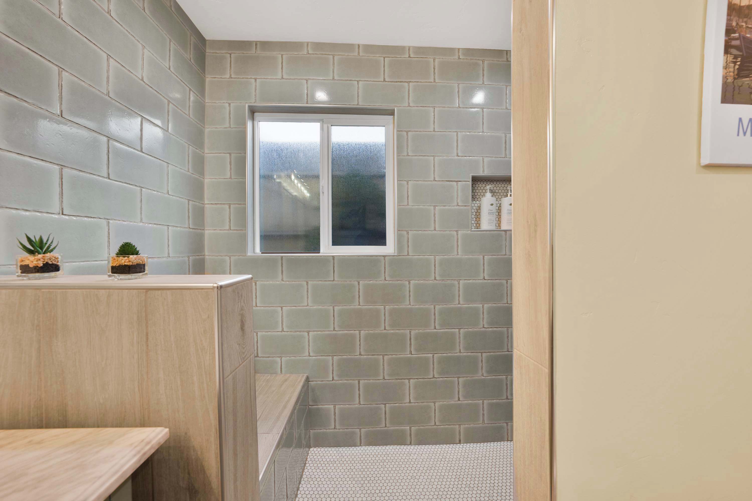 Une salle de bain avec un mur carrelé, une fenêtre et une étagère contenant des articles de toilette.