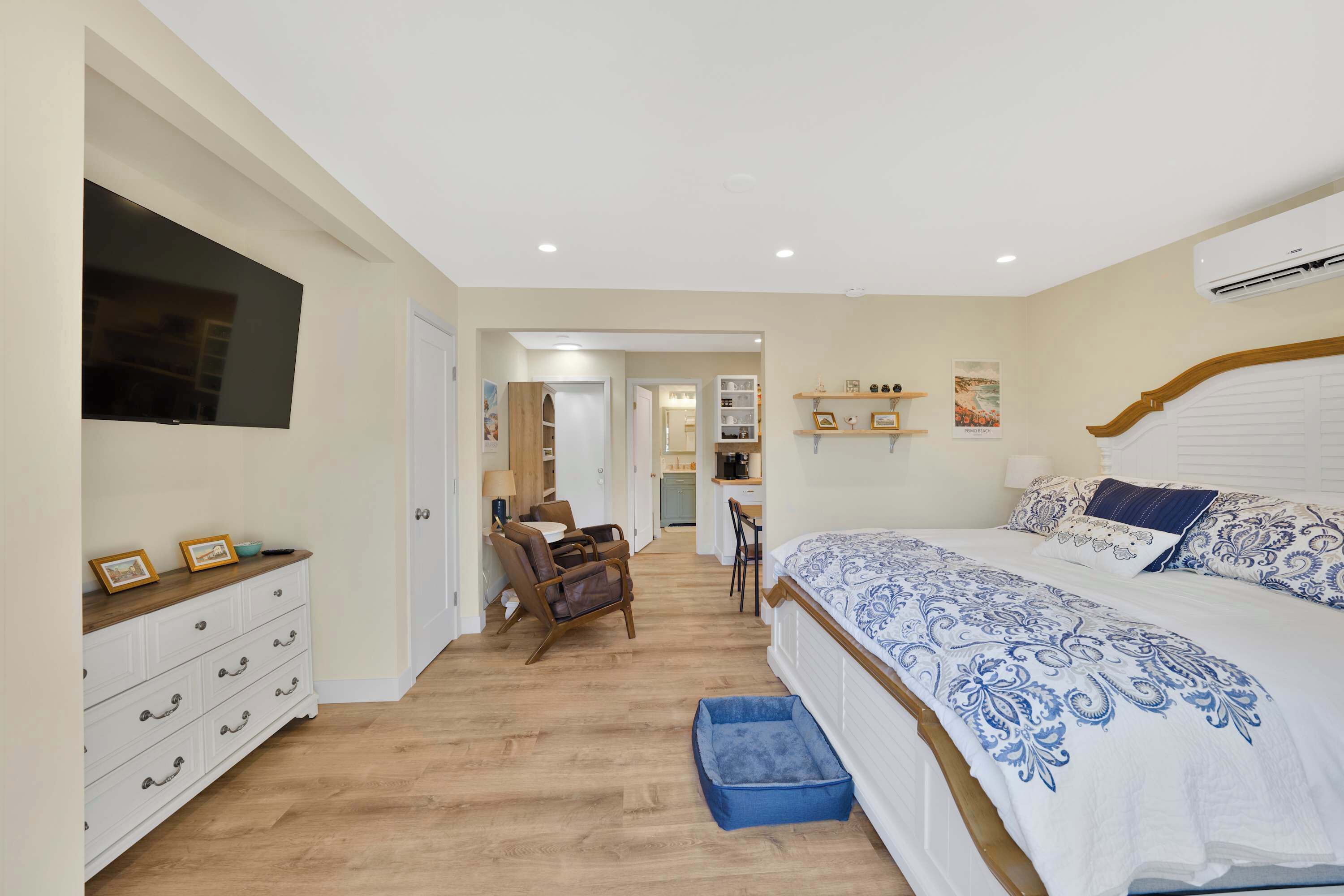 A bedroom with a bed, dresser, chair, and a small blue pet bed.