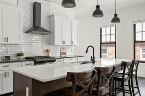 A modern kitchen with white cabinetry, a large island, and pendant lighting.