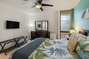 A bedroom with a bed, a ceiling fan, a flat-screen TV, a dresser, a mirror, and a window with curtains. - Kihei Maui Vista Condo | 3 Pools, Walk to Beach, Tennis, Pickleball, AC (Kihei)