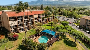 A hotel with a swimming pool, multiple balconies, and a view of the surrounding landscape. - Kihei Maui Vista Condo | 3 Pools, Walk to Beach, Tennis, Pickleball, AC (Kihei)