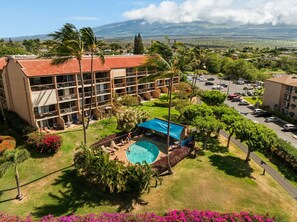 A hotel with a swimming pool, multiple balconies, and a view of the surrounding landscape. - Kihei Maui Vista Condo | 3 Pools, Walk to Beach, Tennis, Pickleball, AC (Kihei)