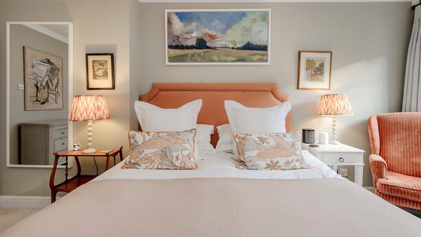 A hotel room with a large bed, two bedside tables, a chair, and artwork on the walls. - Divine Mews House - South Kensington (London)