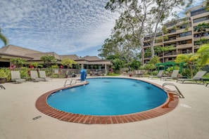 A swimming pool with lounge chairs and a covered area, surrounded by buildings and trees. - Oceanfront Kahana Condo | King Bed, Ocean View, Beachfront, Pool & Sleeps 4 (Lahaina)