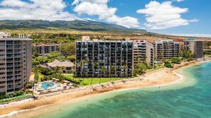 Un hotel frente a la playa con varios edificios altos, una piscina y una extensión de arena.