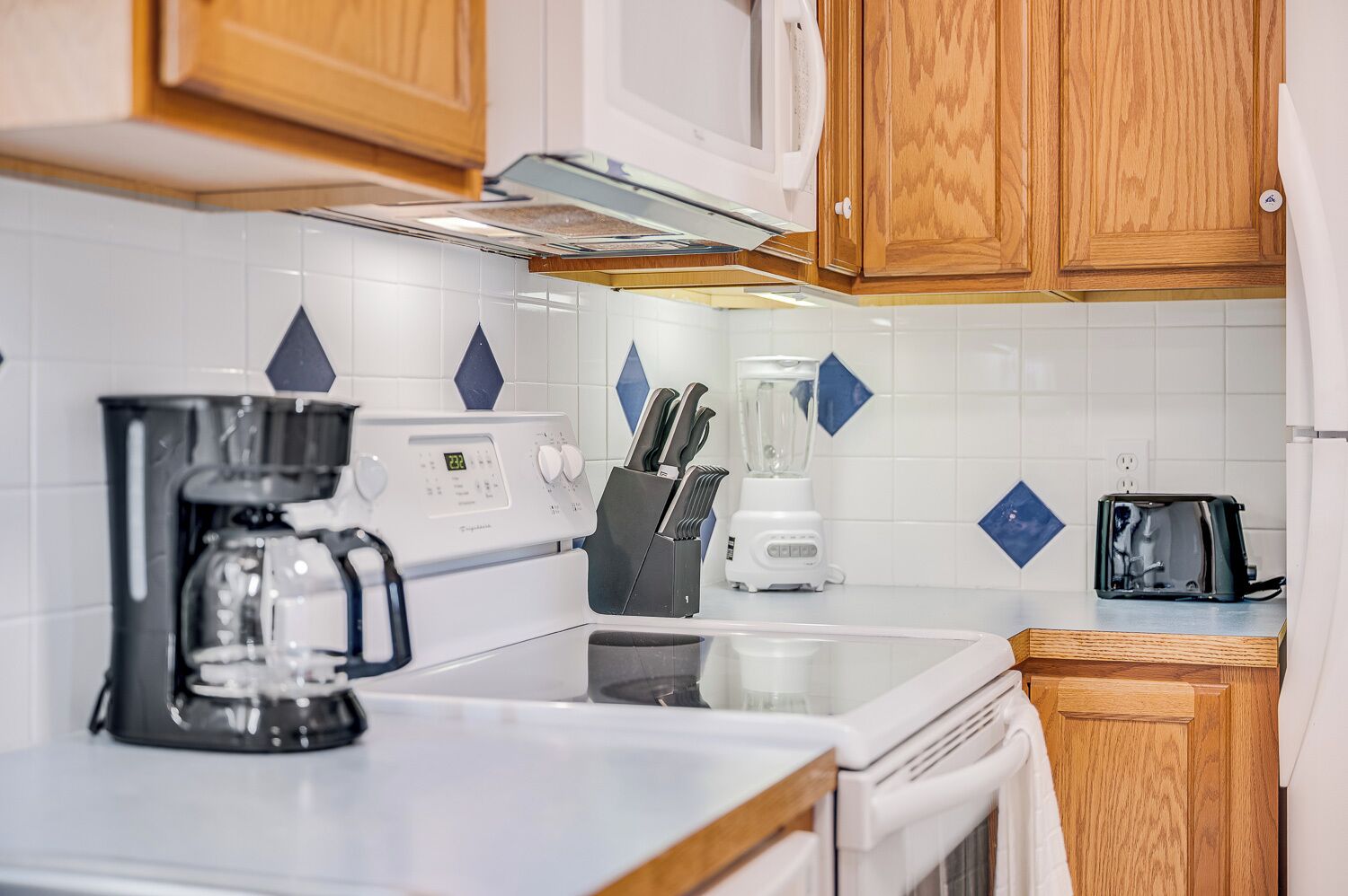 A kitchen with a coffee maker, toaster, blender, and wooden cabinets.