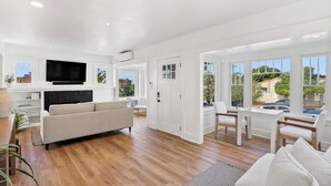A spacious living area with a flat-screen TV, a sofa, and a dining table with chairs. - Steps to La Jolla Cove - Private Outdoor Oasis (San Diego)