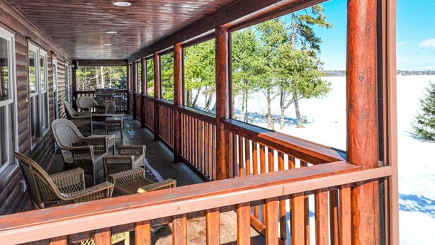 A covered porch with wicker furniture and a view of a snowy landscape. - Pamoola Lodge - Waterfront| sleeps 11+|Private Dock (Rockwood)