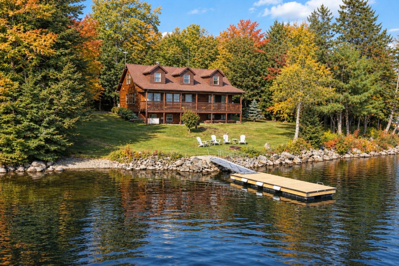 Eine Lodge mit Steg, umgeben von einem See und Herbstlaub.