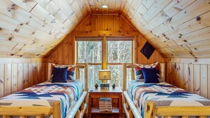A cabin with two beds, a central table, and a window with a view of trees. - Pamoola Lodge - Waterfront| sleeps 11+|Private Dock (Rockwood)