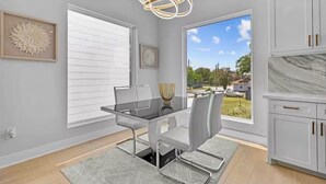 A modern kitchen with white cabinetry, a glass dining table, and a view of the outdoors. - Villa De Briley - Downtown HTX - Fire Pit - Photo Booth!
Luxury Family Retreat (Houston)