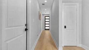 A hallway with white doors, a wooden floor, and a ceiling light. - Villa De Briley - Downtown HTX - Fire Pit - Photo Booth!
Luxury Family Retreat (Houston)