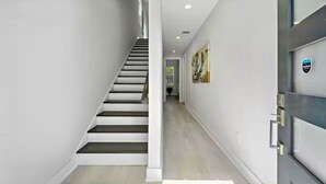 Ein modernes Interieur mit Treppe, Flur und einer Tür mit einem Logo.