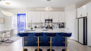 A modern kitchen with white cabinets, a central island with bar stools, and a stainless steel refrigerator. - Villa De Briley - Downtown HTX - Fire Pit - Photo Booth!
Luxury Family Retreat (Houston)