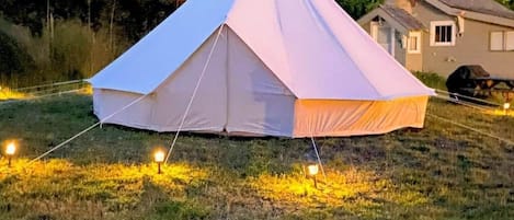A white tent set up on grass with a house in the background.