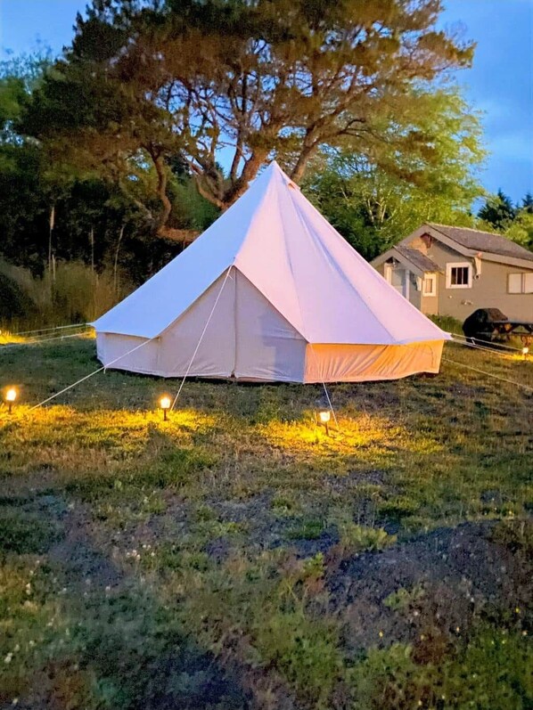 A white tent set up on grass with a house in the background.