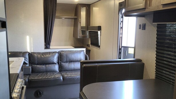 A compact RV interior with a kitchenette, a dining area, and a seating space. - Lovely 1-bedroom recreational vehicle with AC in Sacramento near Rancho Cordova (Sacramento)