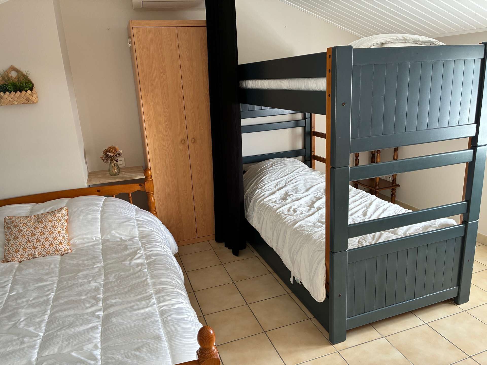 Un lit superposé avec une tête de lit en bois et un lit inférieur agrémenté d’un coussin à motifs.