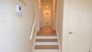Un escalier menant à une porte, avec un interrupteur et une grille d’aération sur le mur.