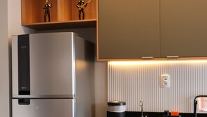 Una cocina moderna con refrigerador integrado, un lavamanos y un estante de madera con dos figurillas.