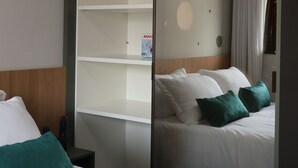 Habitación de hotel con cama, mesita de noche, control remoto, espejo y una planta en la pared.