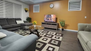 Ein Wohnzimmer mit Sofa, Couchtisch, Fernseher und Zimmerpflanzen.