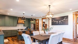A modern kitchen with dark green cabinets, a central island, and pendant lighting. - It Was All a Dream at Eagles Nest - fireplaces, Springs (Banner Elk)