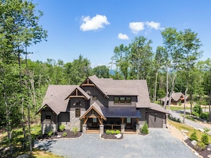A large, multi-story house with a stone facade, multiple chimneys, and a well-maintained driveway. - It Was All a Dream at Eagles Nest - fireplaces, Springs (Banner Elk)