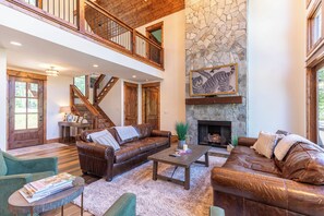 A spacious living area with a stone fireplace, leather sofas, and a wooden staircase. - It Was All a Dream at Eagles Nest - fireplaces, Springs (Banner Elk)