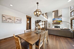 Ein Essbereich mit einem Holztisch, Stühlen, einer Chandelüster und Bildern an den Wänden.