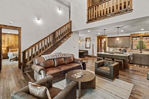 A spacious living area with a leather sofa, a coffee table, and a staircase. - Running Bear Lodge at Eagles Nest - community amenities (Banner Elk)