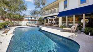 A swimming pool with a deck, lounge chairs, and a building with a balcony. - Private pool, 3-bedrooms, 3.5 bathrooms, 2-car garage with EV charger, across from beach access (Fernandina Beach)
