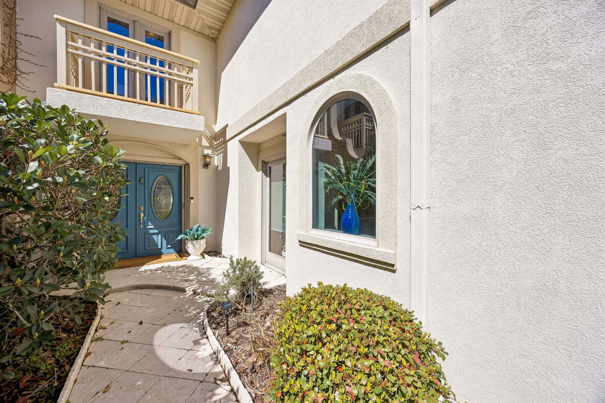 A building with a blue door, a balcony, and a window with a plant.