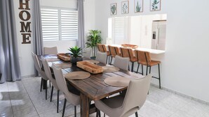 A dining area with a wooden table, beige chairs, and a large 'HOME' sign on the wall. - Hacienda Yagrumo - Spacious 4-bedroom house - Mountain Retreat with River (Utuado)