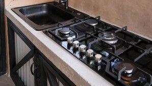A kitchen with a gas stove, a sink, and wooden paneling. - Hacienda Yagrumo - Spacious 4-bedroom house - Mountain Retreat with River (Utuado)